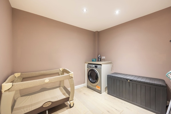A laundry room with a washing machine, a drying rack, and a baby changing station.