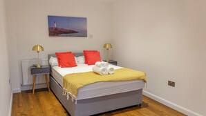 A neatly arranged bedroom with a bed, two bedside tables with lamps, a radiator, and a painting on the wall. - Modern Main Door Flat Edinburgh City Center (Edinburgh)