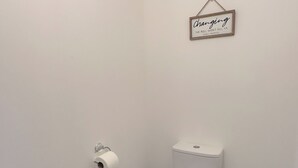 A small, clean bathroom with a toilet, a roll of toilet paper, a radiator, and a beige rug. - Modern Main Door Flat Edinburgh City Center (Edinburgh)