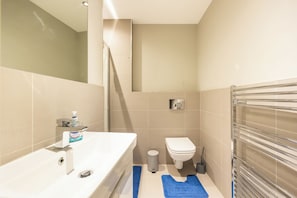 Un baño pequeño con lavamanos, inodoro y ducha.