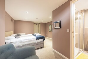 A bedroom with a bed, a bedside table, a chair, a door leading to a bathroom, and a wall-mounted mirror.