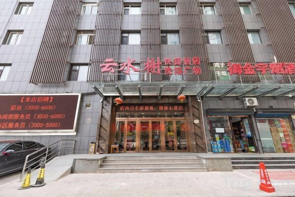 A building with a large entrance, multiple windows, and a signboard with contact information.
