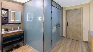 Une salle de bain moderne avec une cloison en verre, un lavabo avec un miroir et une porte en bois.