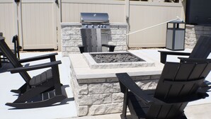 An outdoor patio with a stone fire pit, a grill, and Adirondack chairs. - King 1BR + pool near the Walmart NWA Championship (Rogers)