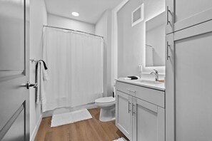 A bathroom with a shower, toilet, and sink.