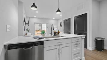 A modern kitchen with white cabinetry, a dishwasher, a sink, and pendant lighting.