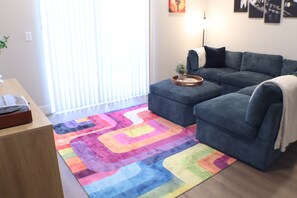 Un salon avec un canapé, une table basse et un tapis coloré.