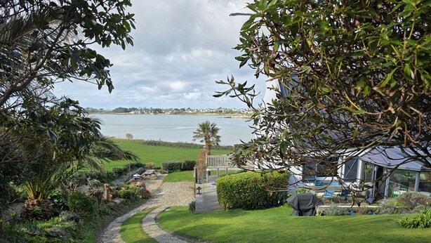 A stone pathway leading to a house with a view of a lake and distant buildings. - Beautiful house with incredible sea view over Aber Wrach (Landéda)