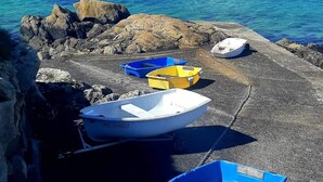 A rocky shoreline with several small boats docked on the beach, a lighthouse in the distance, and calm blue waters. - Beautiful house with incredible sea view over Aber Wrach (Landéda)