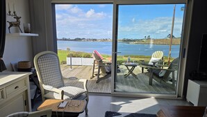 A room with a view of a lake, a dining area with chairs and a table, and a seating area with a chair and a small table. - Beautiful house with incredible sea view over Aber Wrach (Landéda)