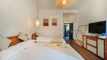 A hotel room with two beds, a television, a wooden cabinet, and a woven ceiling light fixture.