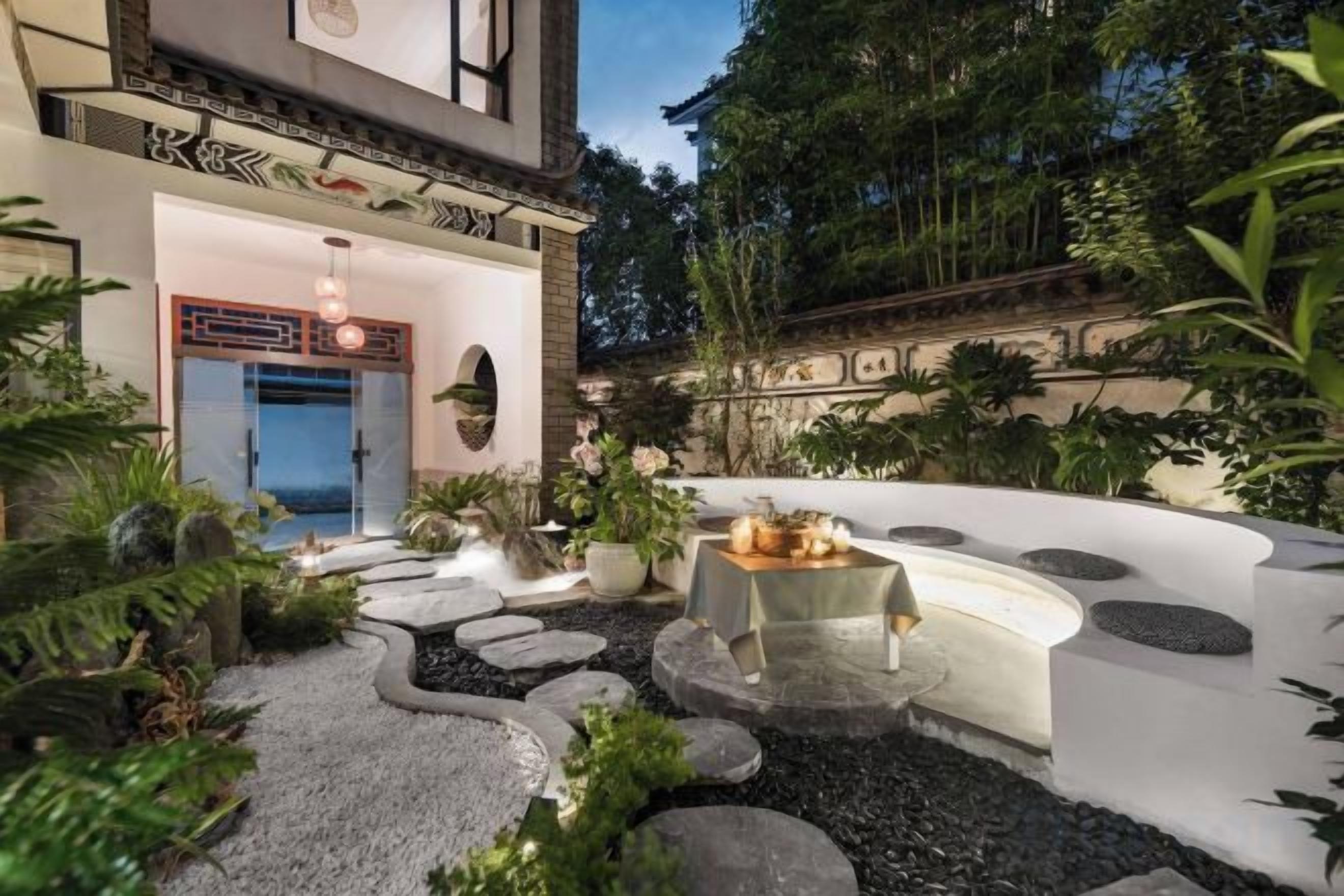 Un jardín cuidado con un sendero de piedra que lleva a una zona de comedor con mesa y sillas.