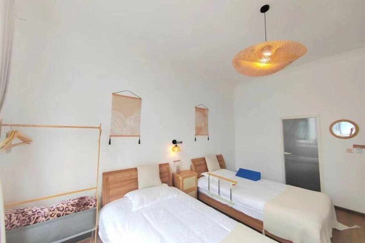 Une chambre d’hôtel avec deux lits, un luminaire suspendu, une armoire et un miroir au mur.
