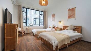 A hotel room with two beds, a desk, a chair, a wardrobe, and a large window.