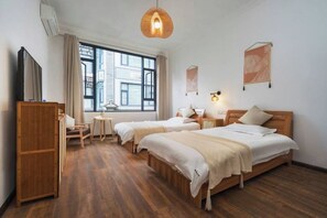 Une chambre d’hôtel avec deux lits, un bureau, une chaise, une armoire et une grande fenêtre.