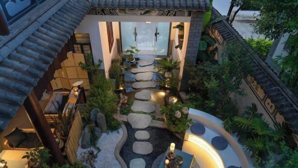 A traditional courtyard with a stone pathway leading to a wooden door, surrounded by potted plants and a small water feature. - Dali Ancient City Shishi Anshe Vacation Apartment (Dali City)