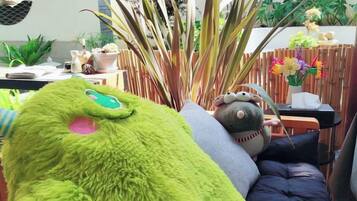 Una habitación con un gran peluche verde, un sofá y una valla de madera.