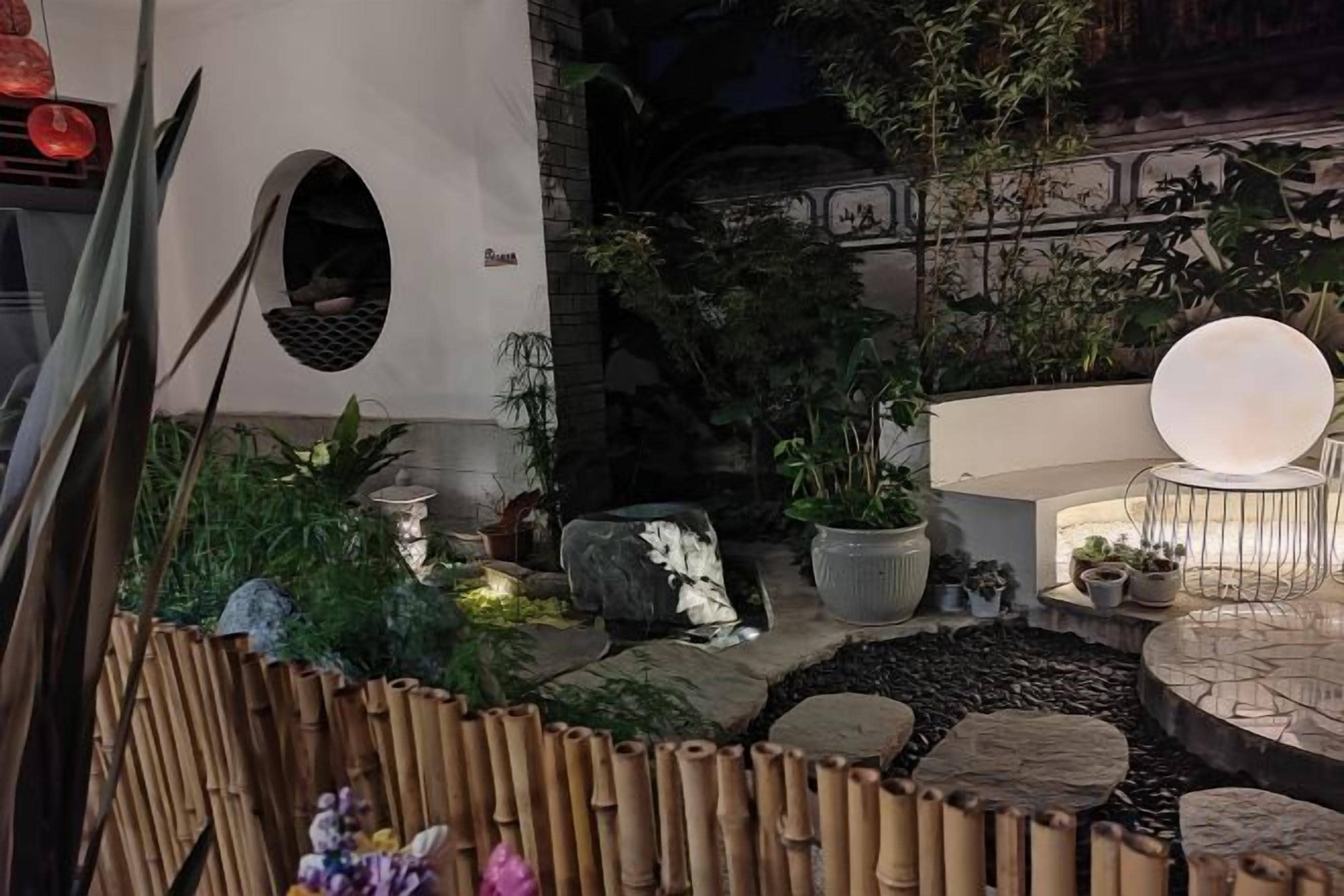 An outdoor garden area with a seating area, potted plants, and a decorative light fixture.