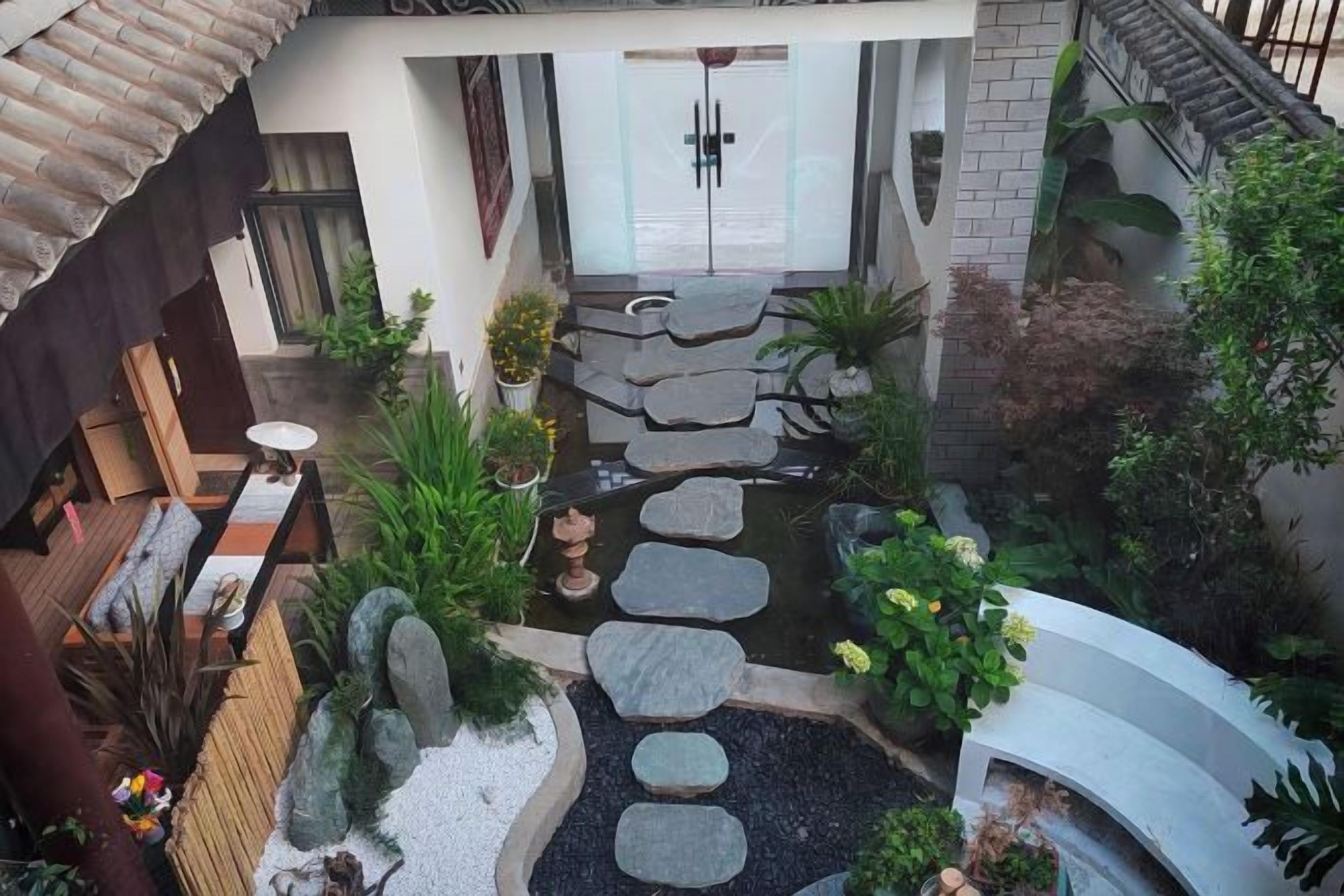 Un patio con un sendero de piedra, zona de estar y plantas en macetas.
