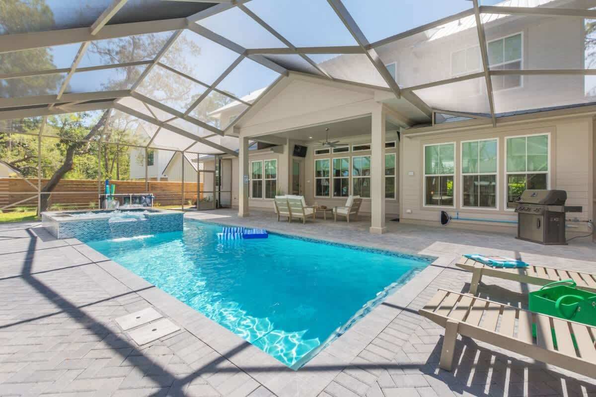 Piscina ao ar livre coberta com área de terraço, cadeiras de descanso e churrasqueira.