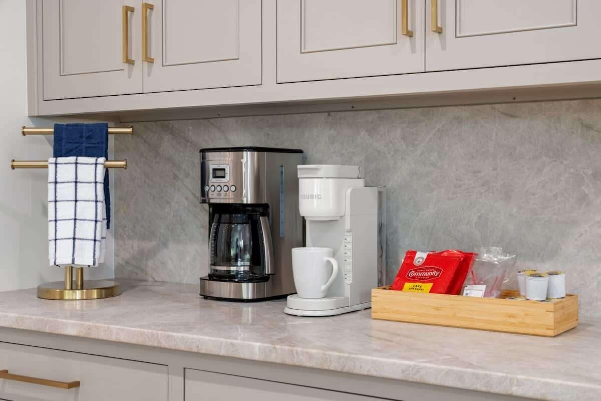 Eine Küche mit Kaffeemaschine, weißer Kaffeekanne und Kapselhalter.