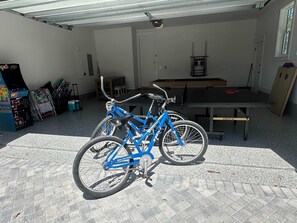 Una habitación con una bicicleta azul, una mesa de ping pong y una pequeña mesa con sillas.
