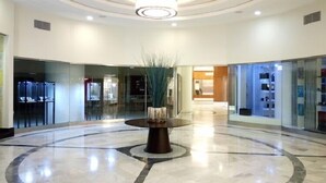 A spacious lobby with a circular marble floor, a central decorative plant, and glass display cases on the walls. - Hotel El Aurassi (Algiers)