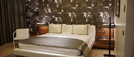 Habitación de hotel moderna con una cama grande, una mesita de noche, una lámpara y una pared con estampado de camuflaje.