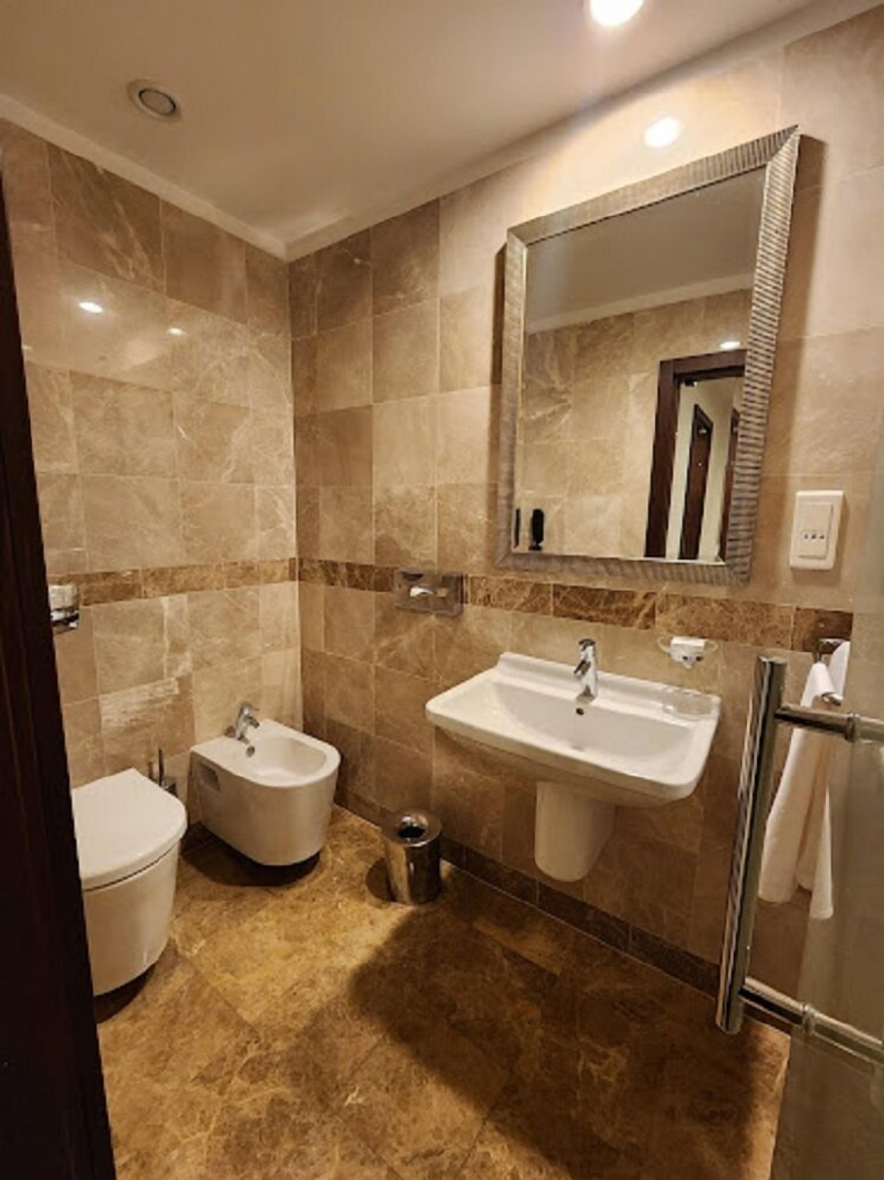 Un baño moderno con un bidé, un lavamanos y un espejo.
