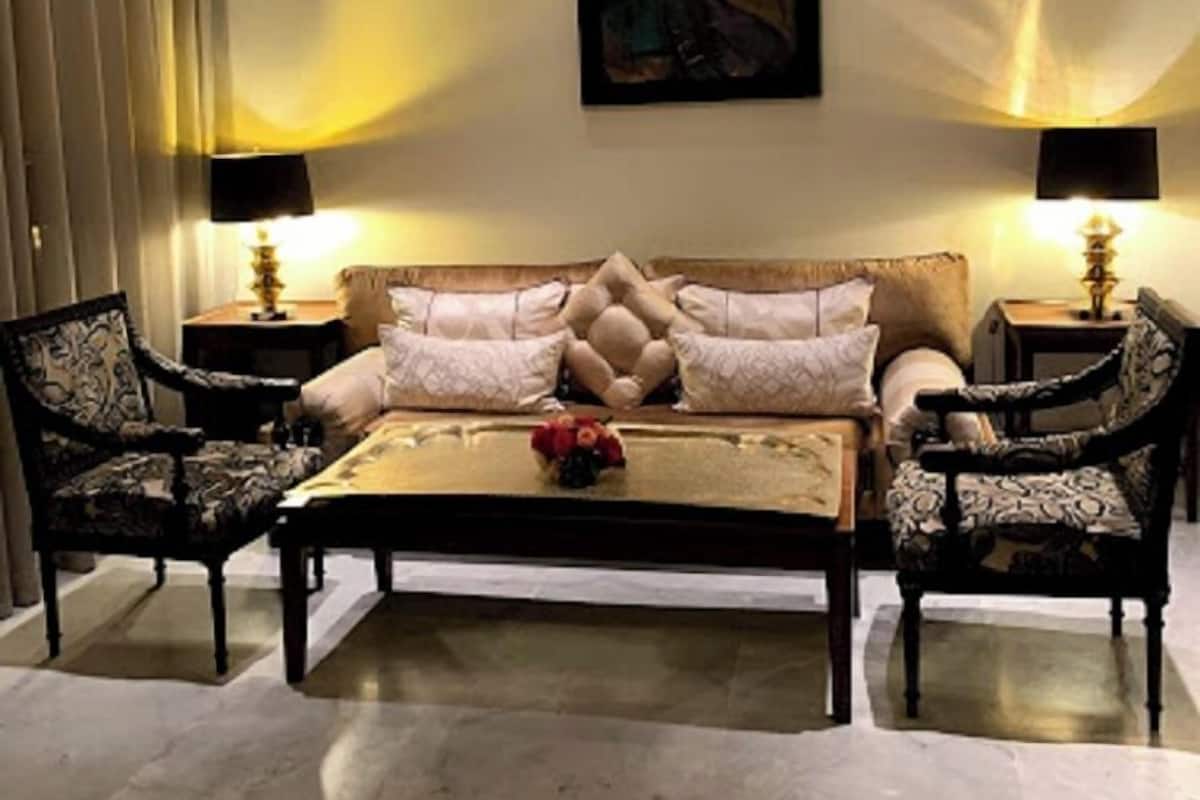 A living room with a sofa, two armchairs, a coffee table, and two floor lamps.