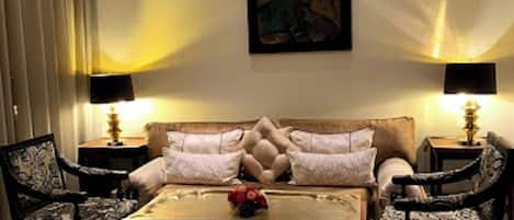 A living room with a sofa, two armchairs, a coffee table, and two floor lamps.