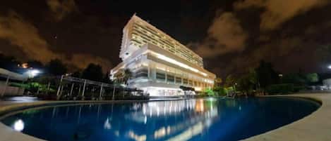 A hotel with a pool at night.