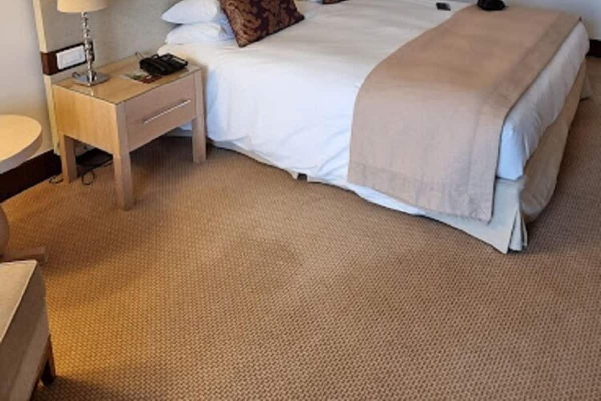 A hotel room with a bed, bedside tables, a lamp, and a framed picture on the wall.