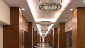 A long, polished hallway with wooden paneling and a reflective floor, leading to a reception area with a chandelier. - Hotel El Aurassi (Algiers)