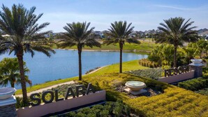 A resort with a sign reading "SOLARA," surrounded by palm trees and a body of water.