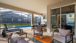 A covered patio area with a pool, outdoor furniture, and a glass door leading to a balcony.
