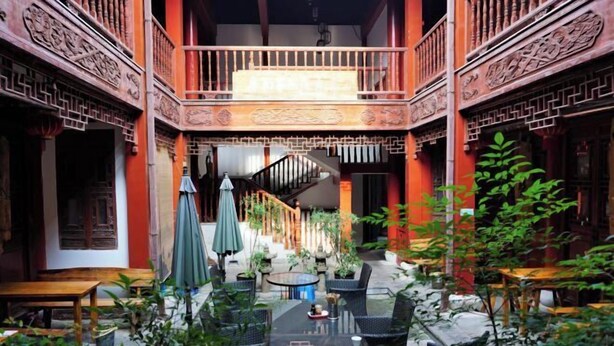 A traditional courtyard with a wooden staircase, outdoor seating, and potted plants. - Fudimen Hotel (Zhenjiang High-speed Railway Station) (Zhenjiang)
