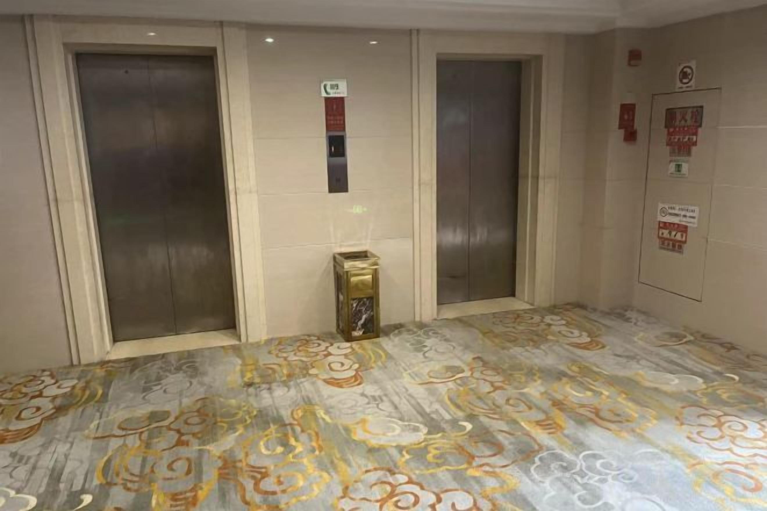 Un área de ascensores con tres elevadores, una pequeña caja decorativa y un letrero en la pared.