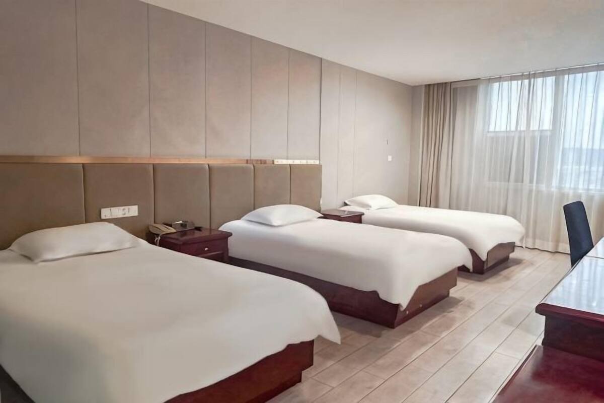 A hotel room with two beds, a desk, and a chair.