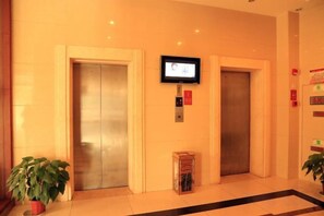 A hotel lobby with two elevators, a television mounted on the wall, and a potted plant. - Fudimen Hotel (Zhenjiang High-speed Railway Station) (Zhenjiang)