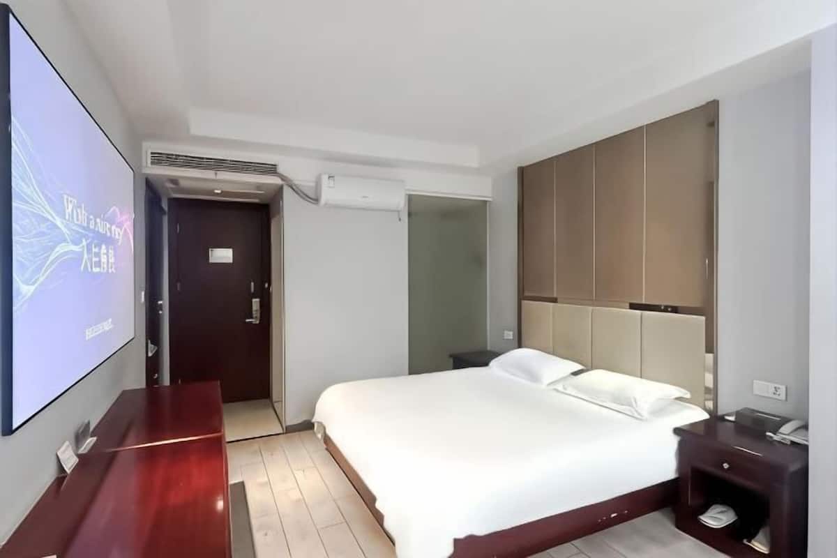 A hotel room with a bed, a TV, a desk, and a wardrobe.
