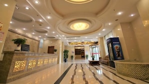 A hotel lobby with a reception desk, seating area, and a large circular light fixture on the ceiling. - Fudimen Hotel (Zhenjiang High-speed Railway Station) (Zhenjiang)