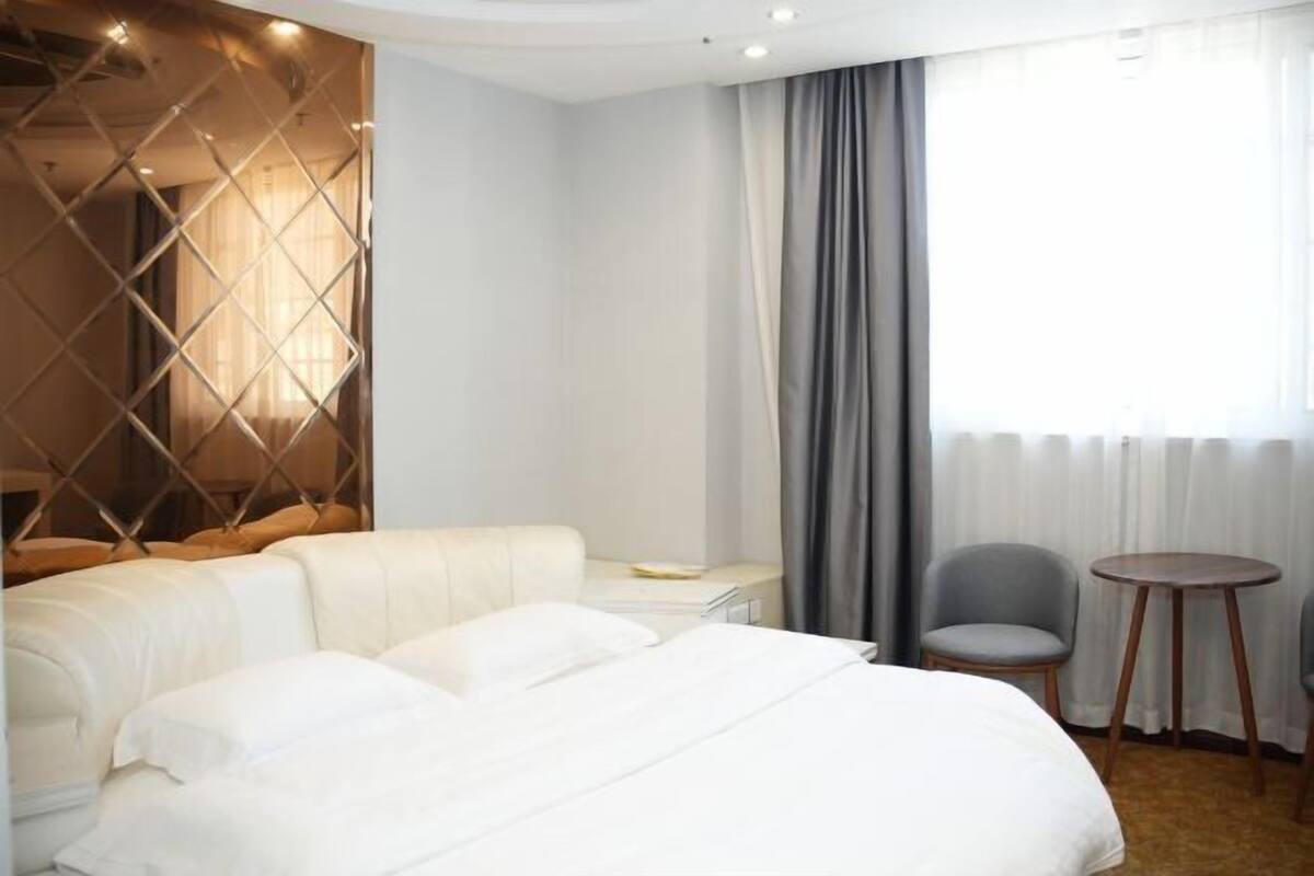 A hotel room with a bed, a desk, a chair, and a small table.