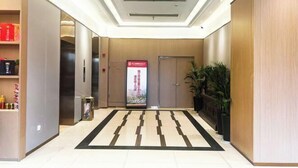 A hotel lobby with a modern design, featuring a reception desk, a digital welcome screen, and a patterned carpet. - Fudimen Hotel (Zhenjiang High-speed Railway Station) (Zhenjiang)