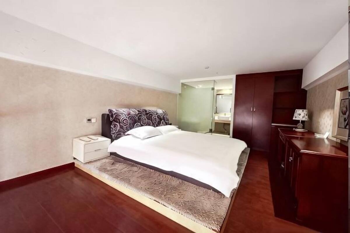 A bedroom with a bed, nightstand, wardrobe, and a mirror.