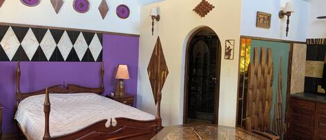 A room with a bed, a table, and a door with a mirror.