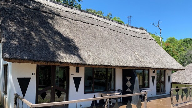 A thatched-roof building with a balcony and a wooden railing. - Sabi Star Accommodation (Mutare)