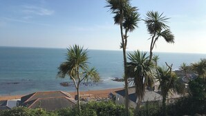 A coastal view with palm trees, a beach, and a stone wall. - Luxury Seacliff Apartment overlooking Ventnor Beach, Sleeps 4 , Ferry Discounts (Ventnor)