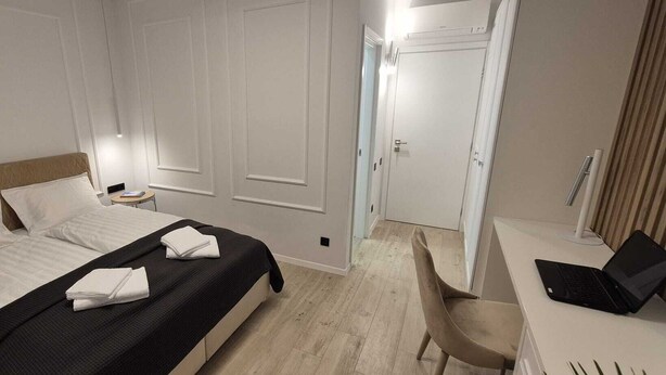 A hotel room with a bed, a desk with a laptop, and a chair. - Anita's mansion (Gattendorf)