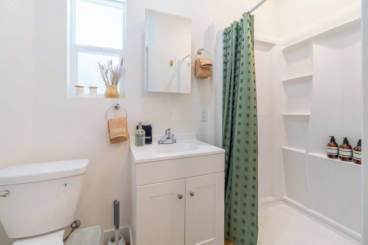 A bathroom with a toilet, sink, mirror, and shower curtain.